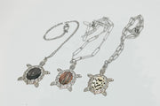 Three Turtle Necklaces on a white background.