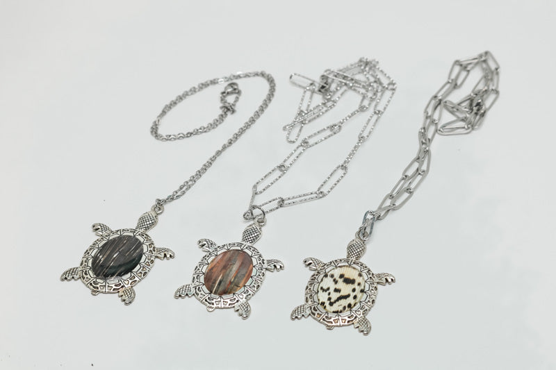 Three Turtle Necklaces on a white background.