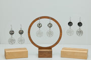 Three pairs of Octopus Earrings on stands on a white background. 