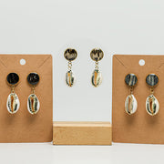 Three pairs of Cowrie Shell Posts on stands on a white background. 