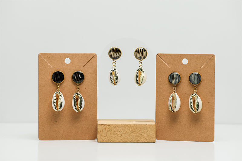 Three pairs of Cowrie Shell Posts on stands on a white background. 
