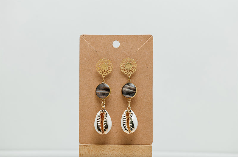 Cowrie Shell Mandala Drops on a cardboard stand on a white background.  