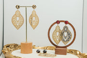 Three pairs of Golden Hour Lace Earrings on stands on a white background with a gold frame. 
