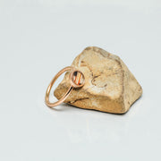 A Mini Rose Gold Ring on a rock on a white background.