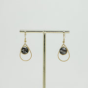 Small Golden Teardrop Earrings on a gold stand on a white background.