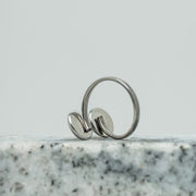 A Silver Double Pendant Adjustable Ring on black and white marble on a white background.