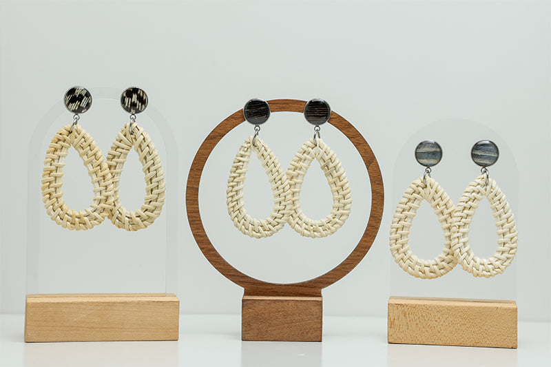 Three pairs of Boho Rattan Teardrop Earrings on stands on a white background. 