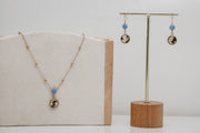 Necklace and earrings on display with a neutral background