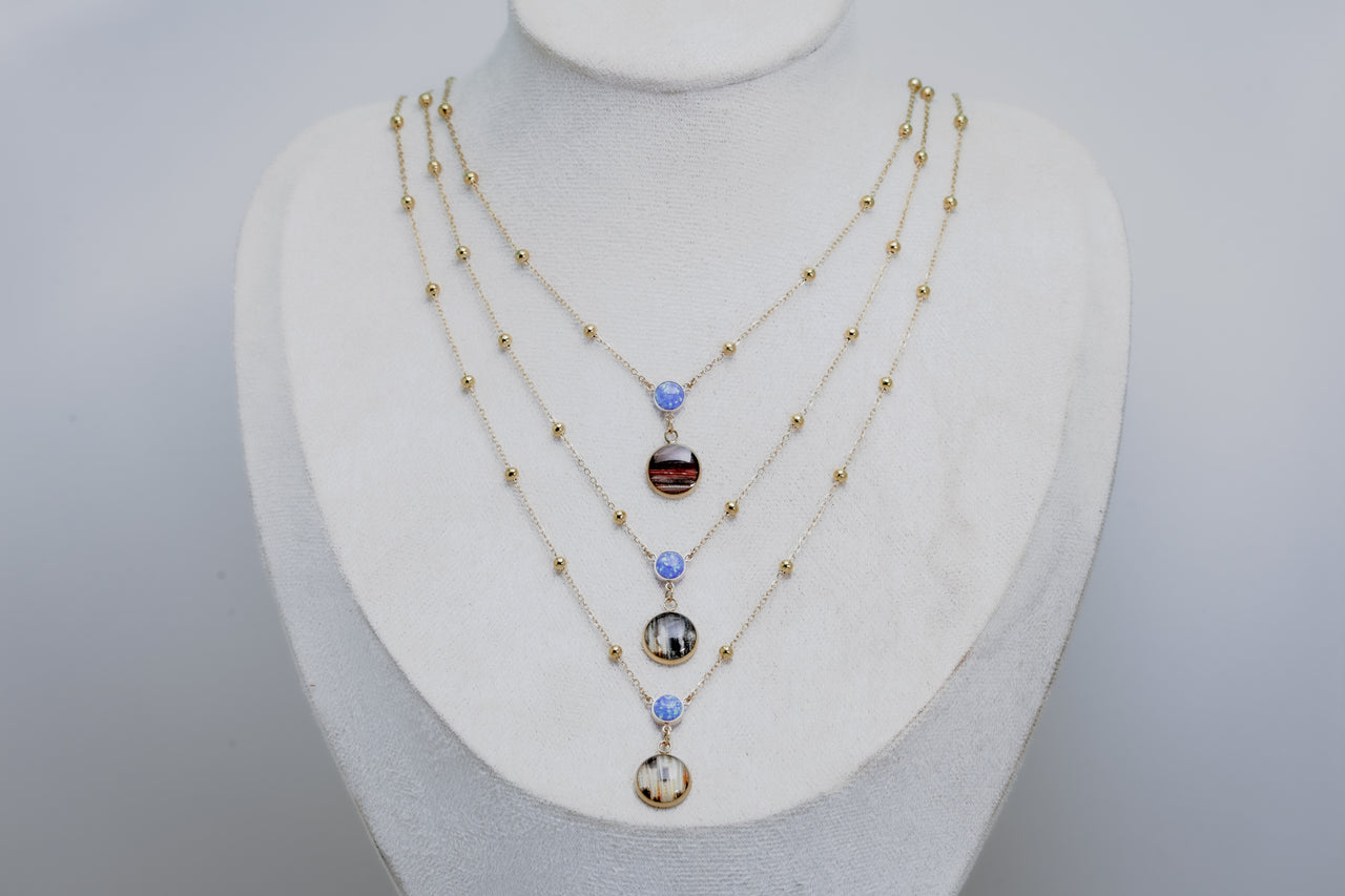 Three Necklaces with blue opal beads on a mannequin bust against a gray background