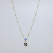 Necklace with a lionfish pelvic fin charm and blue opal on a white background