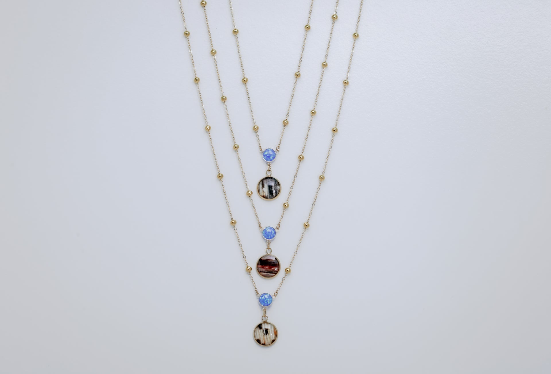 Three layered necklaces with blue opals on a light gray background