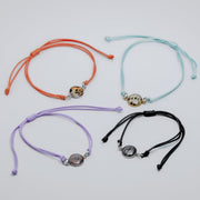 Four colorful bracelets with charms on a light gray background