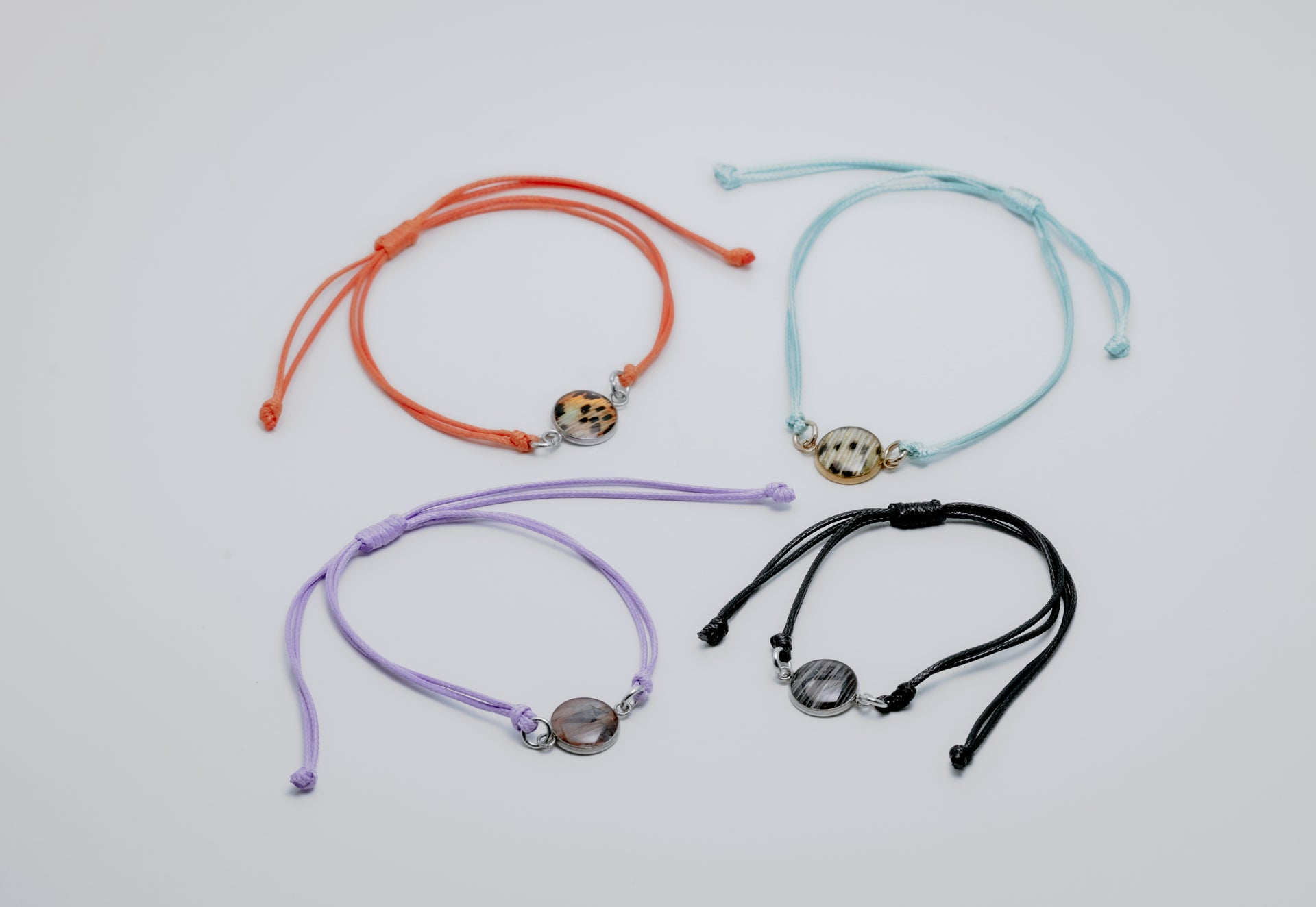 Four colorful bracelets with charms on a light gray background