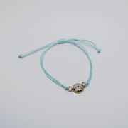Aqua bracelet with a lionfish charm on a light gray background