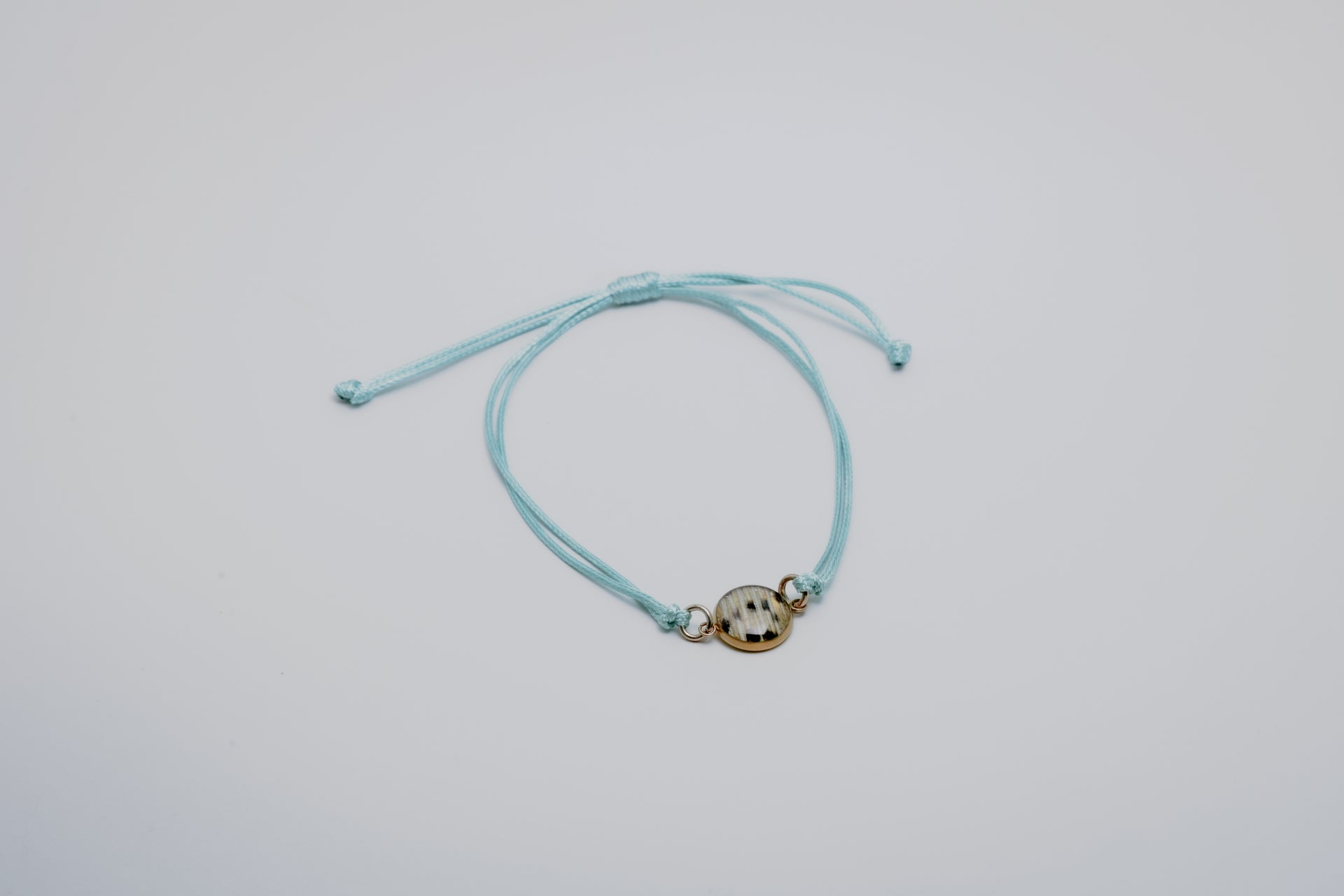 Aqua bracelet with a lionfish charm on a light gray background