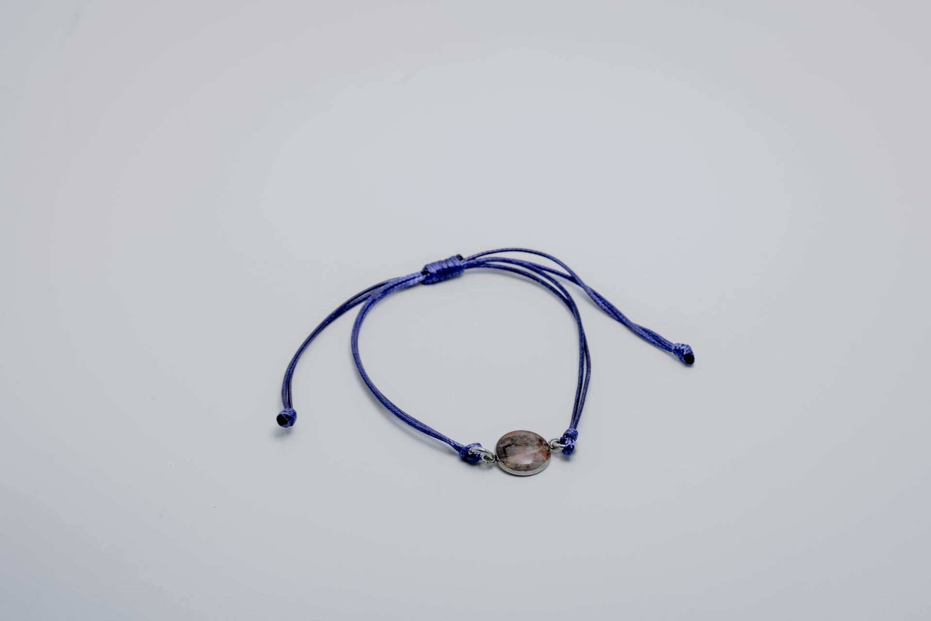 Navy bracelet with a lionfish charm on a light gray background