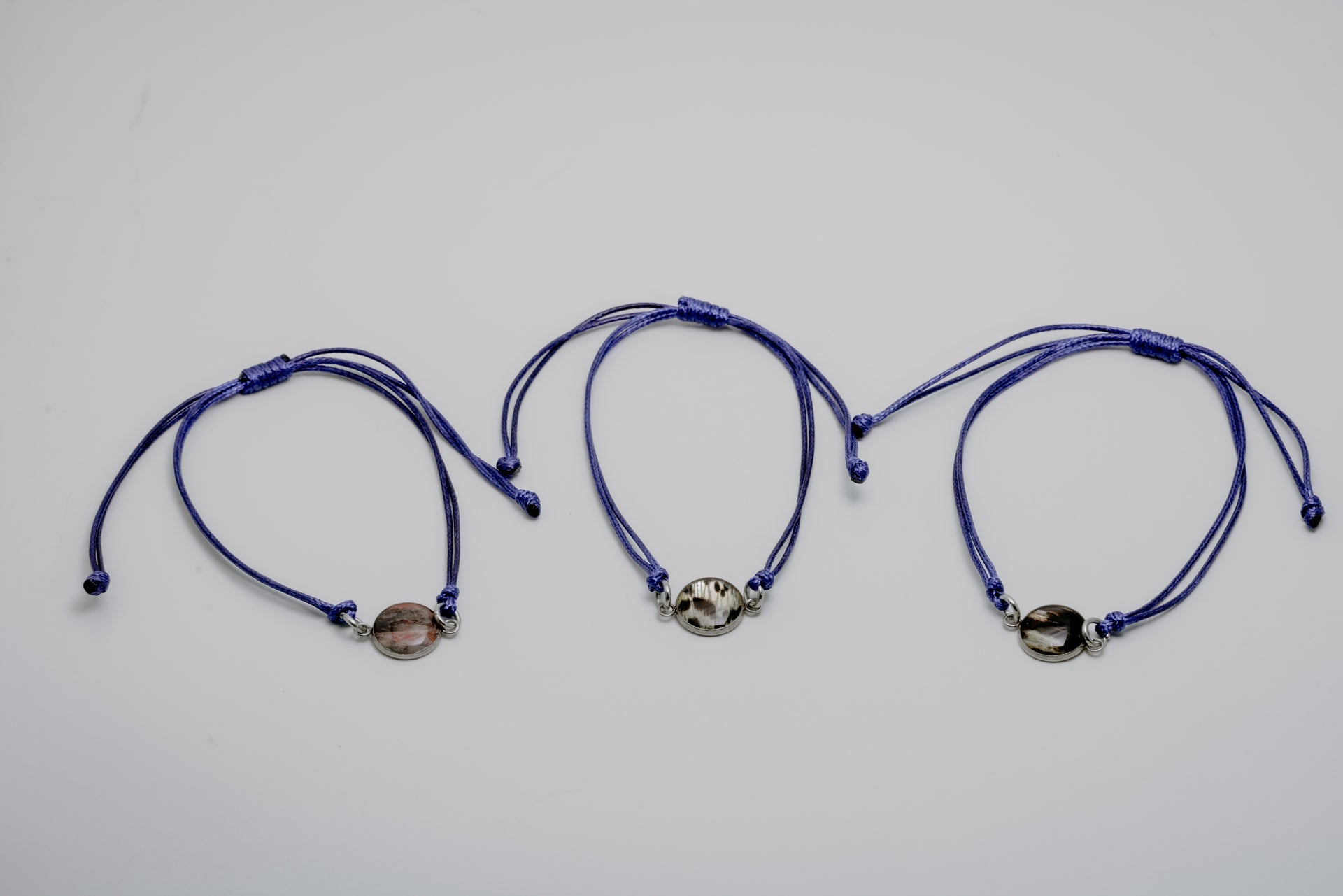 Three blue bracelets with lionfish charms on a light gray background