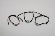 Three black bracelets with lionfish charms on a light gray background