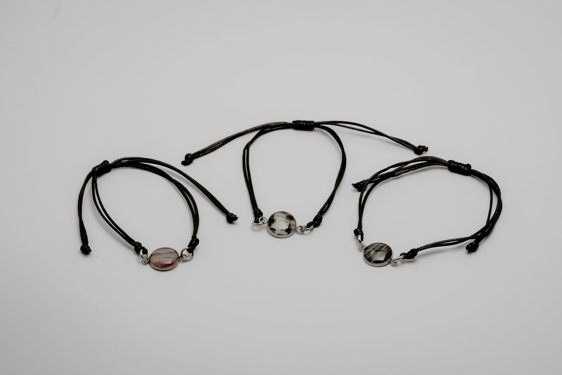 Three black bracelets with lionfish charms on a light gray background