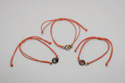Three orange bracelets with lionfish charms on a light gray background