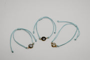 Three aqua bracelets with lionfish charms on a light gray background