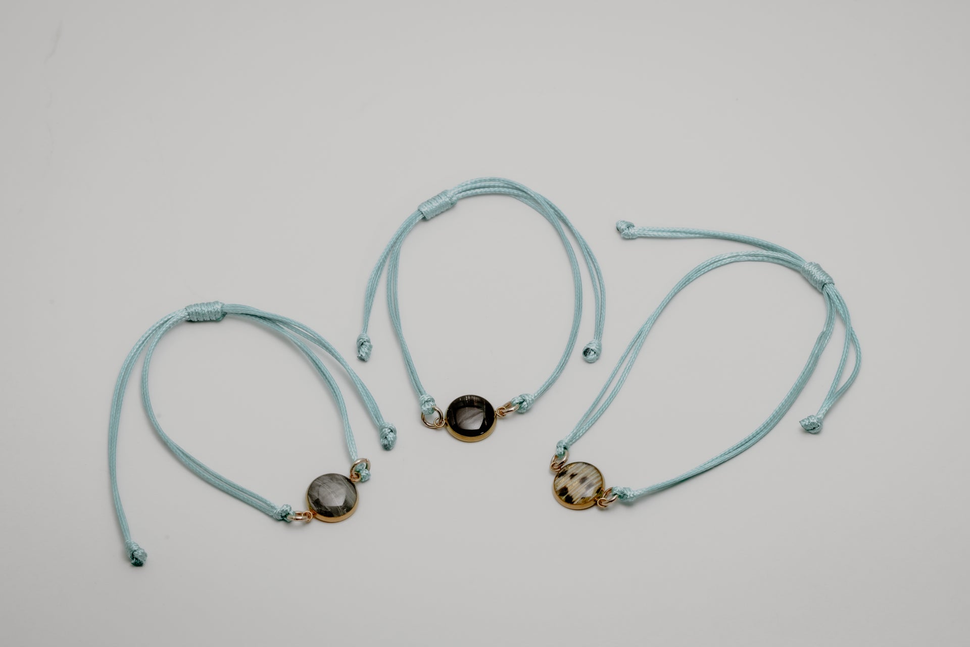 Three aqua bracelets with lionfish charms on a light gray background
