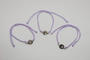 Three purple bracelets with lionfish charms on a light gray background