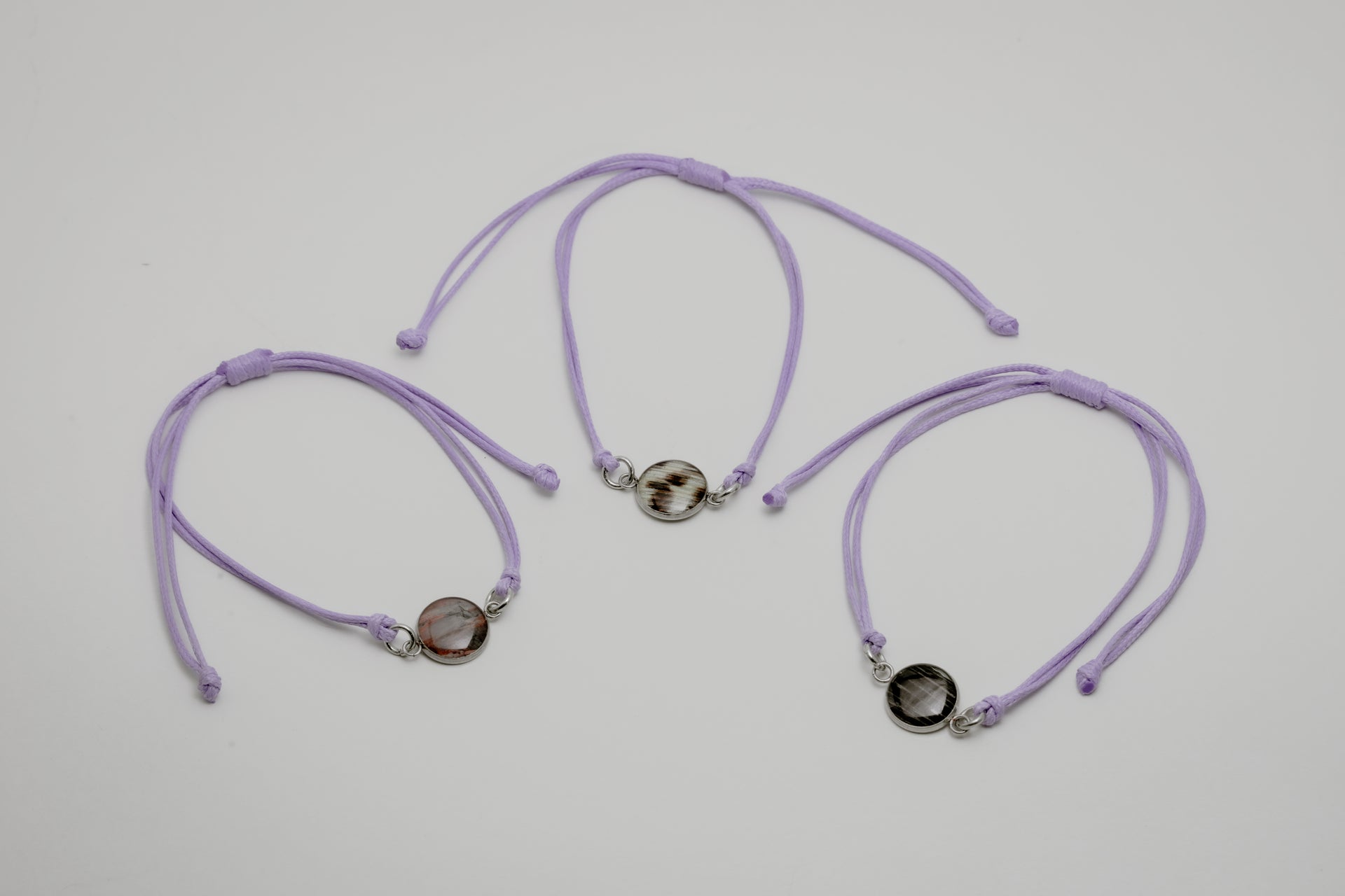 Three purple bracelets with lionfish charms on a light gray background