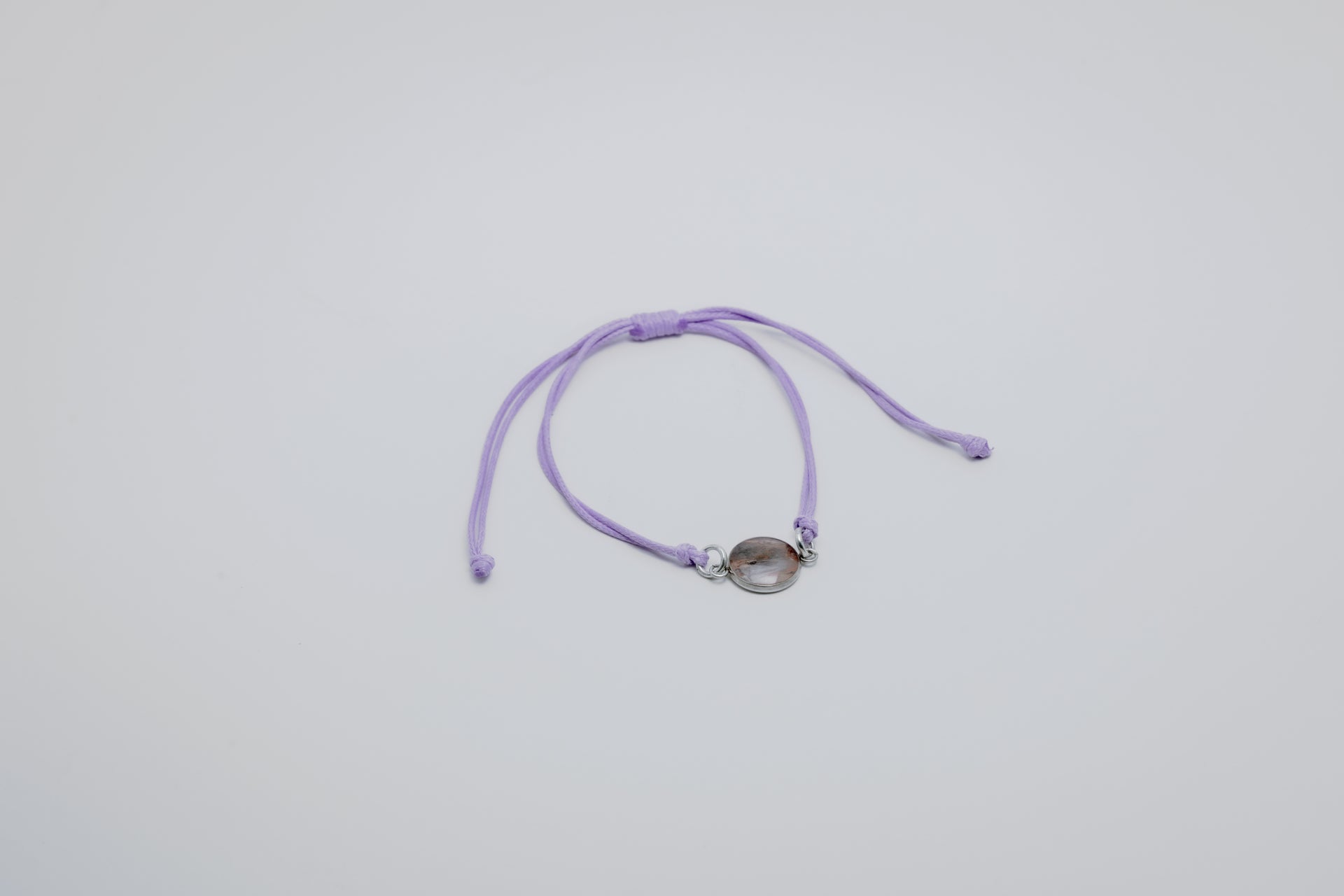Purple bracelet with a lionfish charm on a light gray background