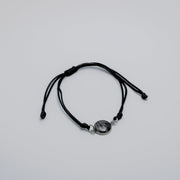 Black bracelet with a lionfish charm on a light gray background