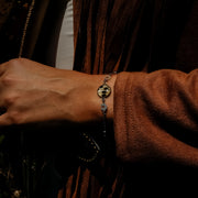 Person wearing a bracelet with a brown jacket and blurred background