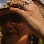 Close-up of a person wearing a straw hat and jewelry outdoors