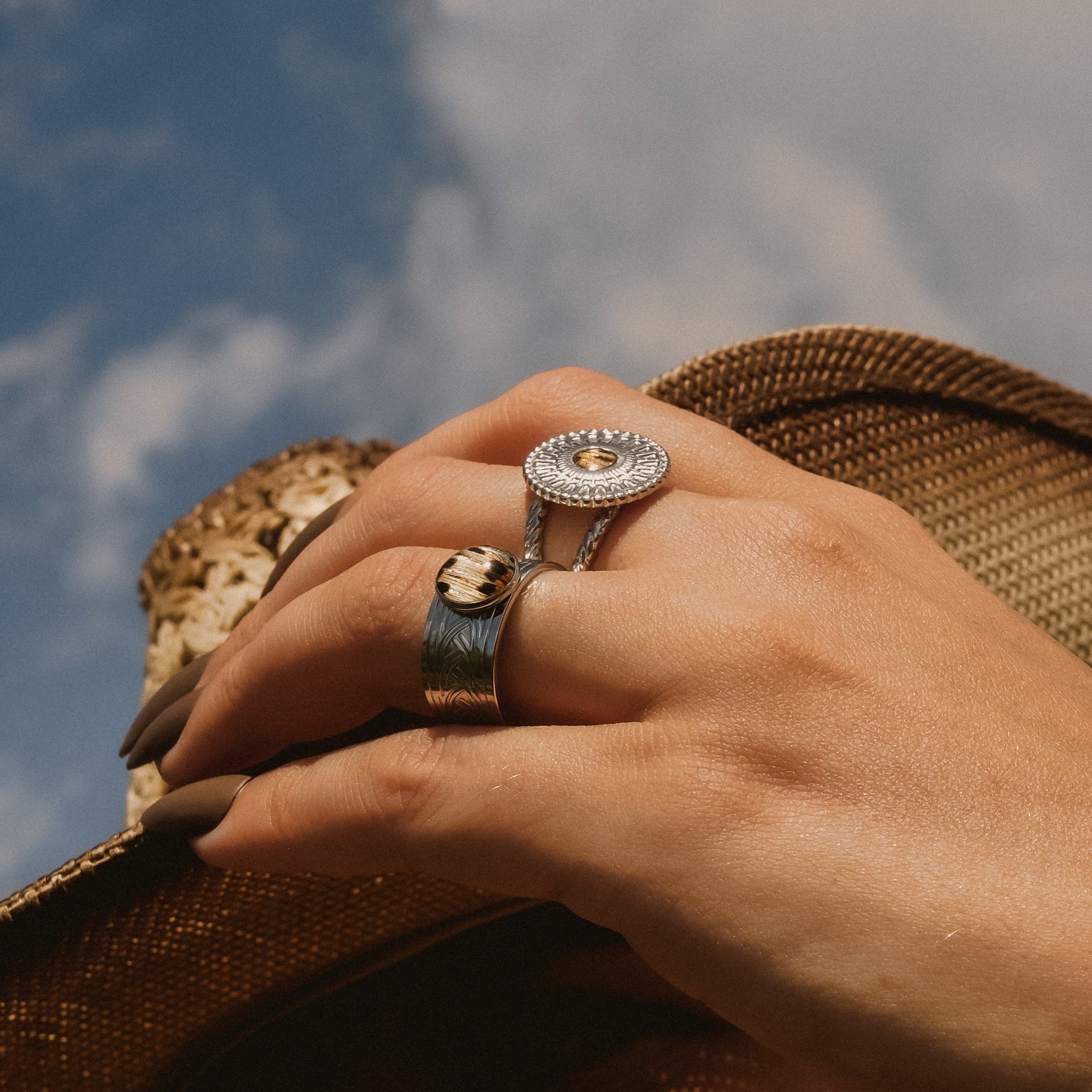 Hand wearing two rings with a blurred natural background