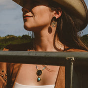 Woman wearing a cowboy hat and leather jacket with a scenic background
