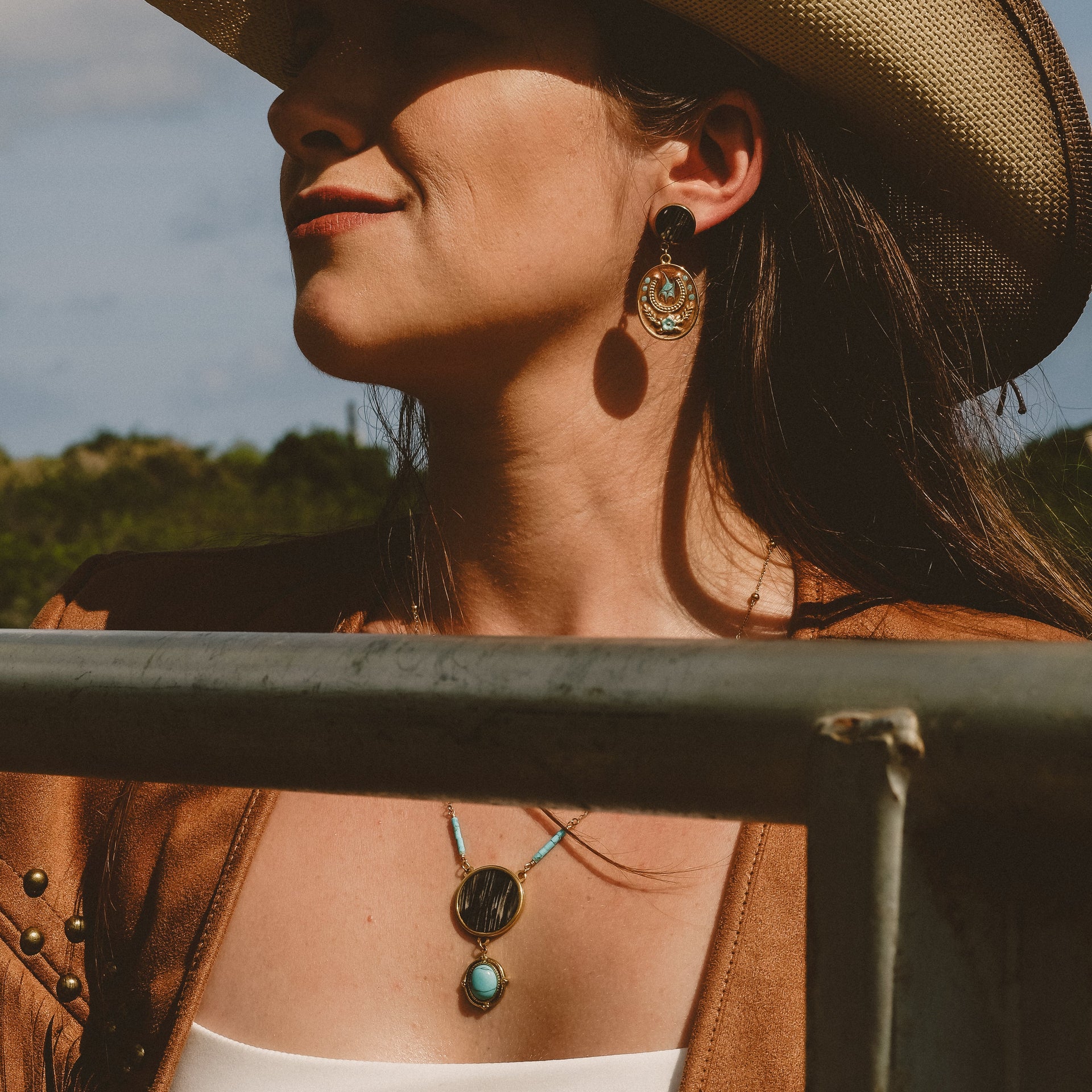 Woman wearing a cowboy hat and leather jacket with a scenic background