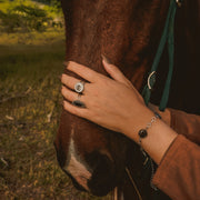 Person petting a horse with a ring and bracelet on a natural background