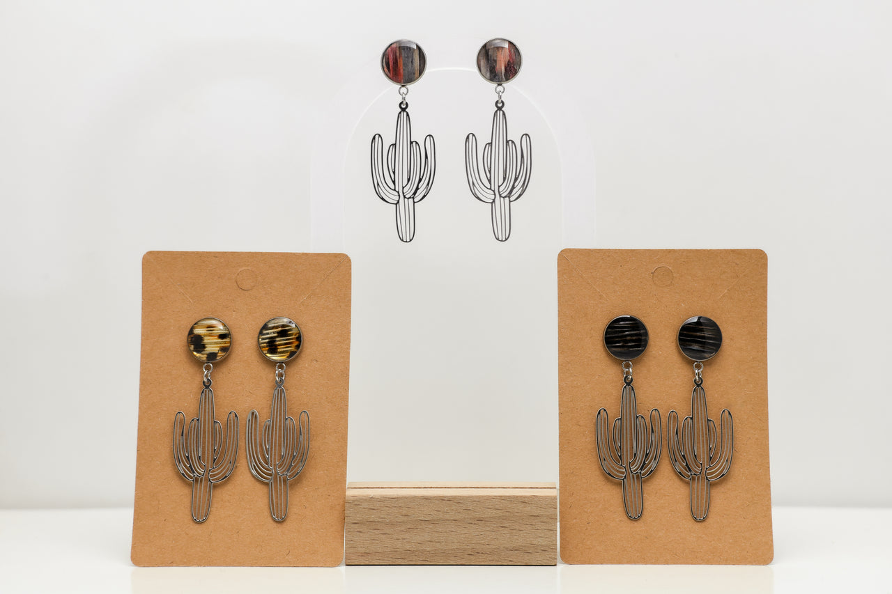 Cactus-shaped earrings with lionfish fins on display cards against a white background