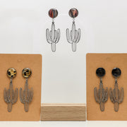 Cactus-shaped earrings with lionfish fins on display cards against a white background