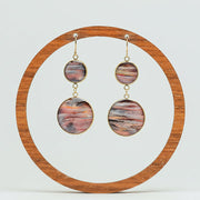 Dual Lionfish Gold Dangles on a wooden circular earring stand on a white background.  