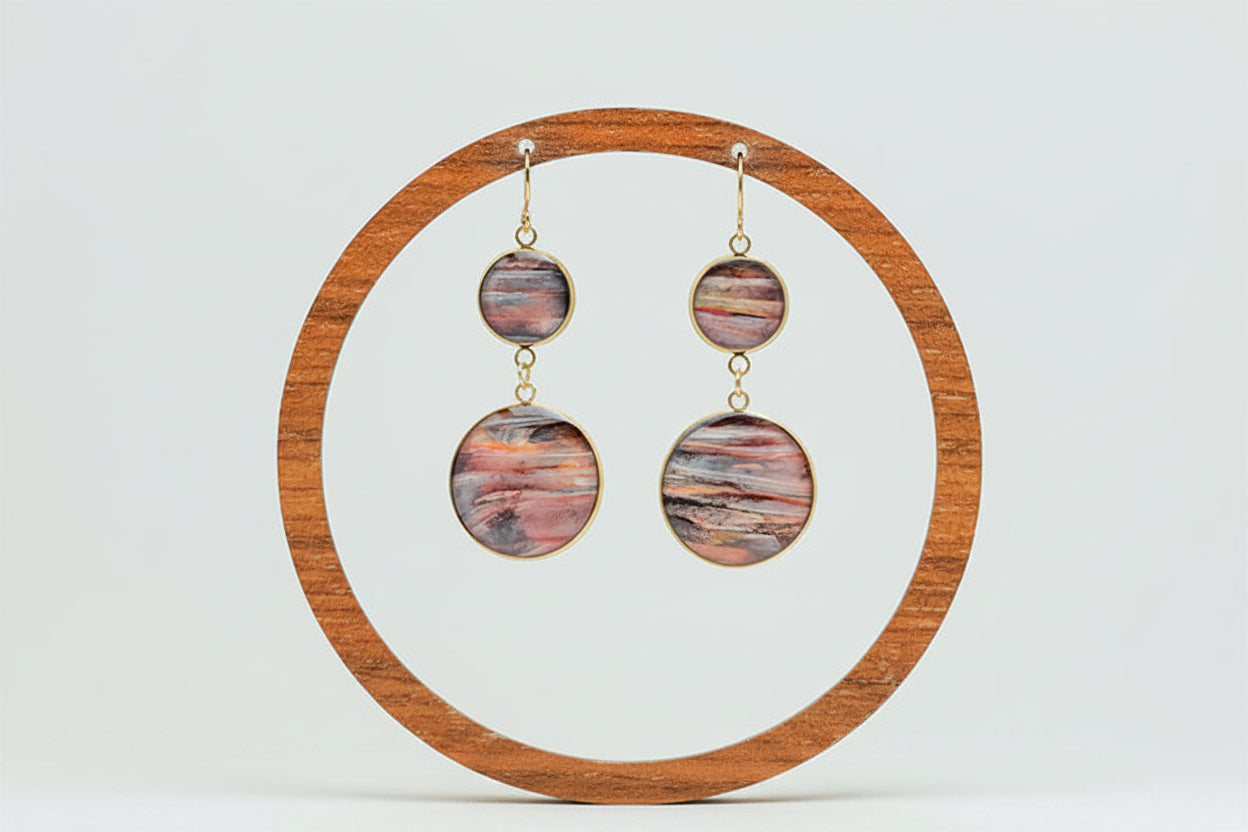 Dual Lionfish Gold Dangles on a wooden circular earring stand on a white background.  