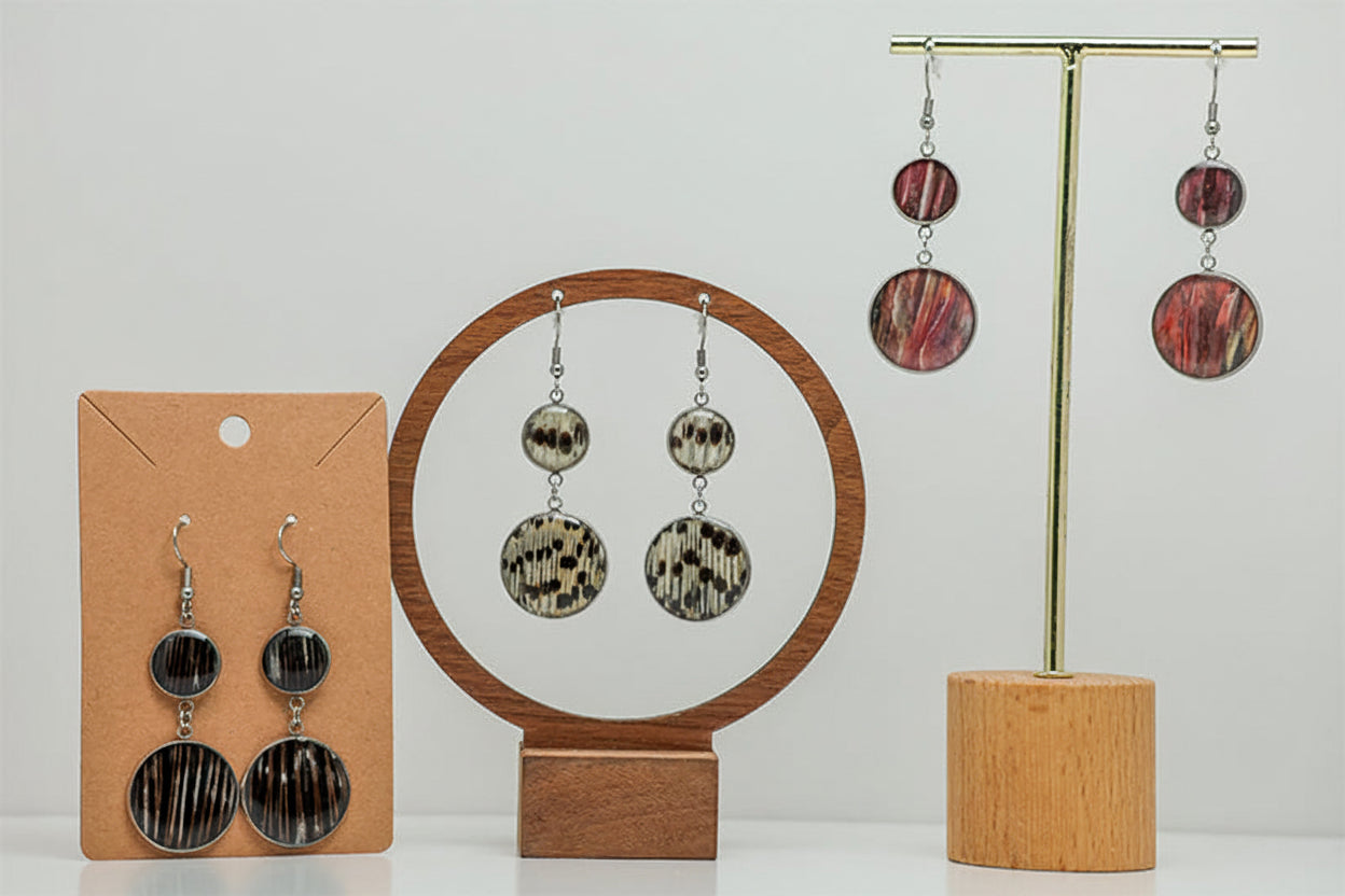 Three pairs of Dual Lionfish Silver Dangle earrings featuring tail, pectoral and pelvic fin types displayed on stands on a white background.