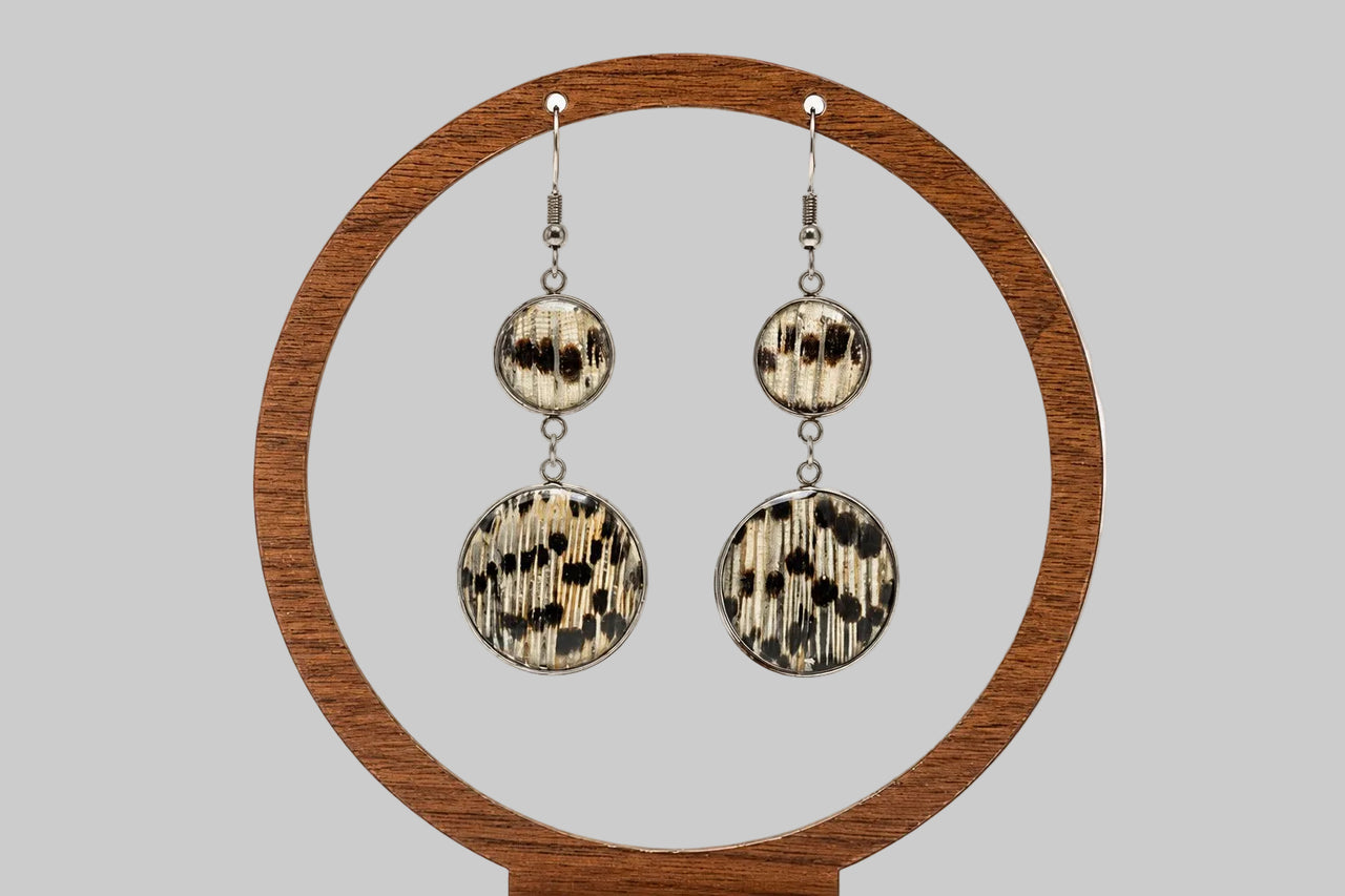 Dual Lionfish Silver Dangle earrings with tail fin pendants displayed on a circular wooden stand on a white background.  