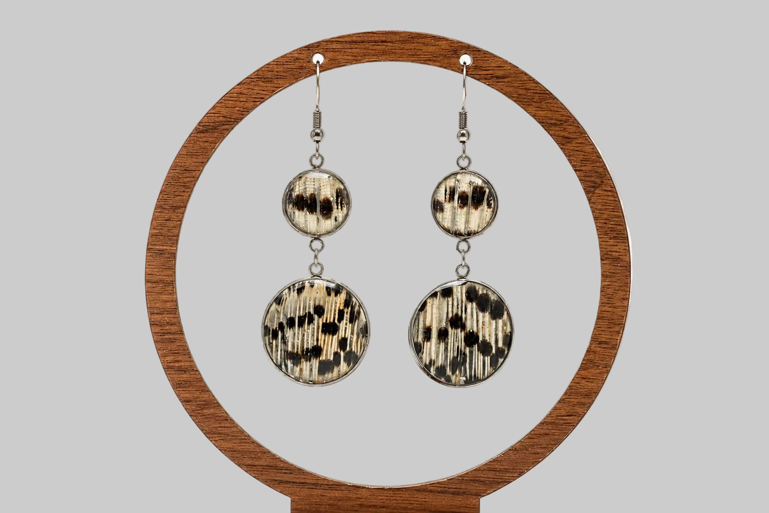 Dual Lionfish Silver Dangle earrings with tail fin pendants displayed on a circular wooden stand on a white background.  