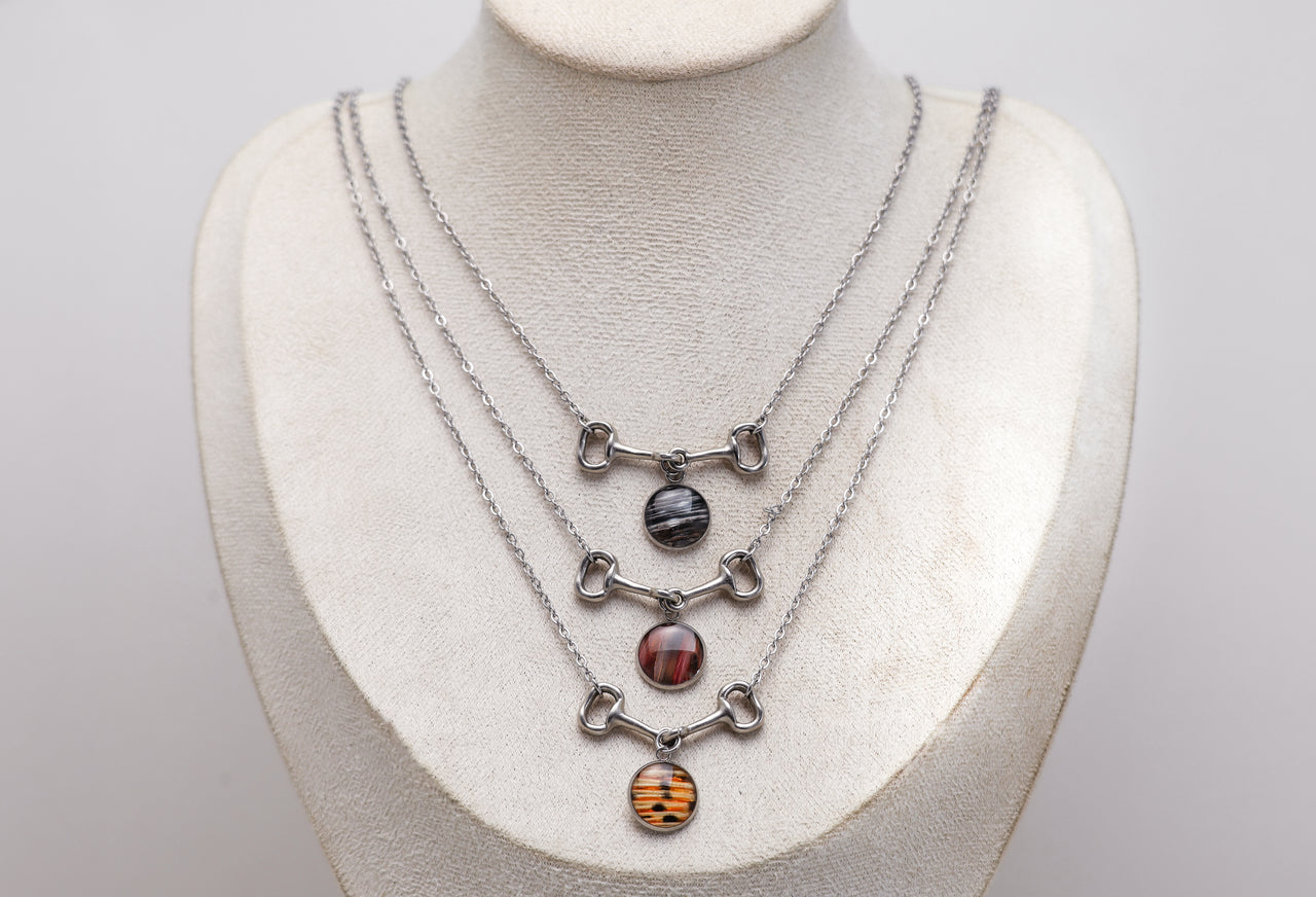 Three necklaces with different colored lionfish stones on a mannequin bust.