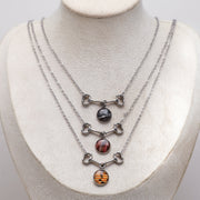 Three necklaces with different colored lionfish stones on a mannequin bust.