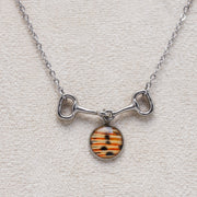 Silver lionfish bit necklace with striped pendant on a neutral textured background