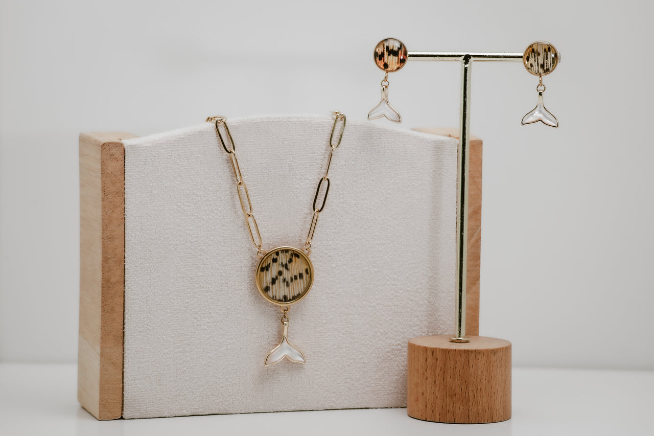 Jewelry set with freshwater pearl whale tail necklace and earrings on a wooden stand and box.