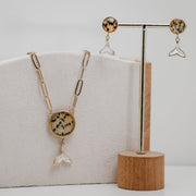 Jewelry set with freshwater pearl whale tail necklace and earrings on a wooden stand and box.