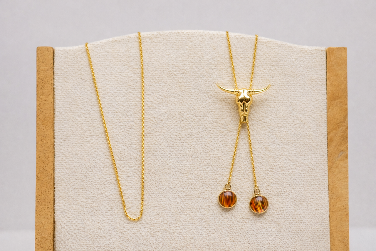Gold necklace with amber lionfish fins on a display card against a gray background
