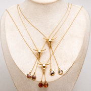 Set of gold necklaces with pendant lionfish fin drops on a mannequin bust.